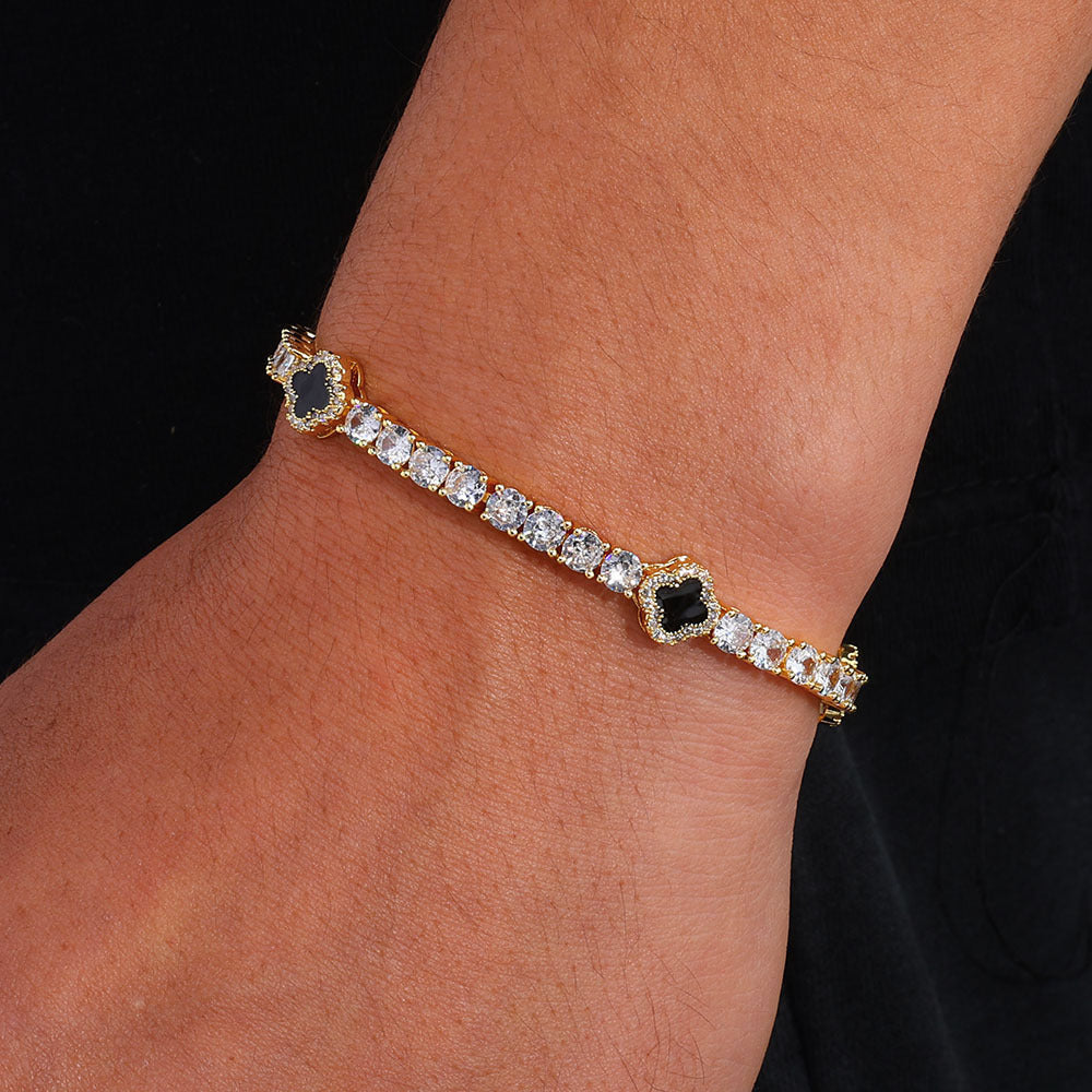 The model showcases the black enamel clover motifs tennis bracelet with gold plating.