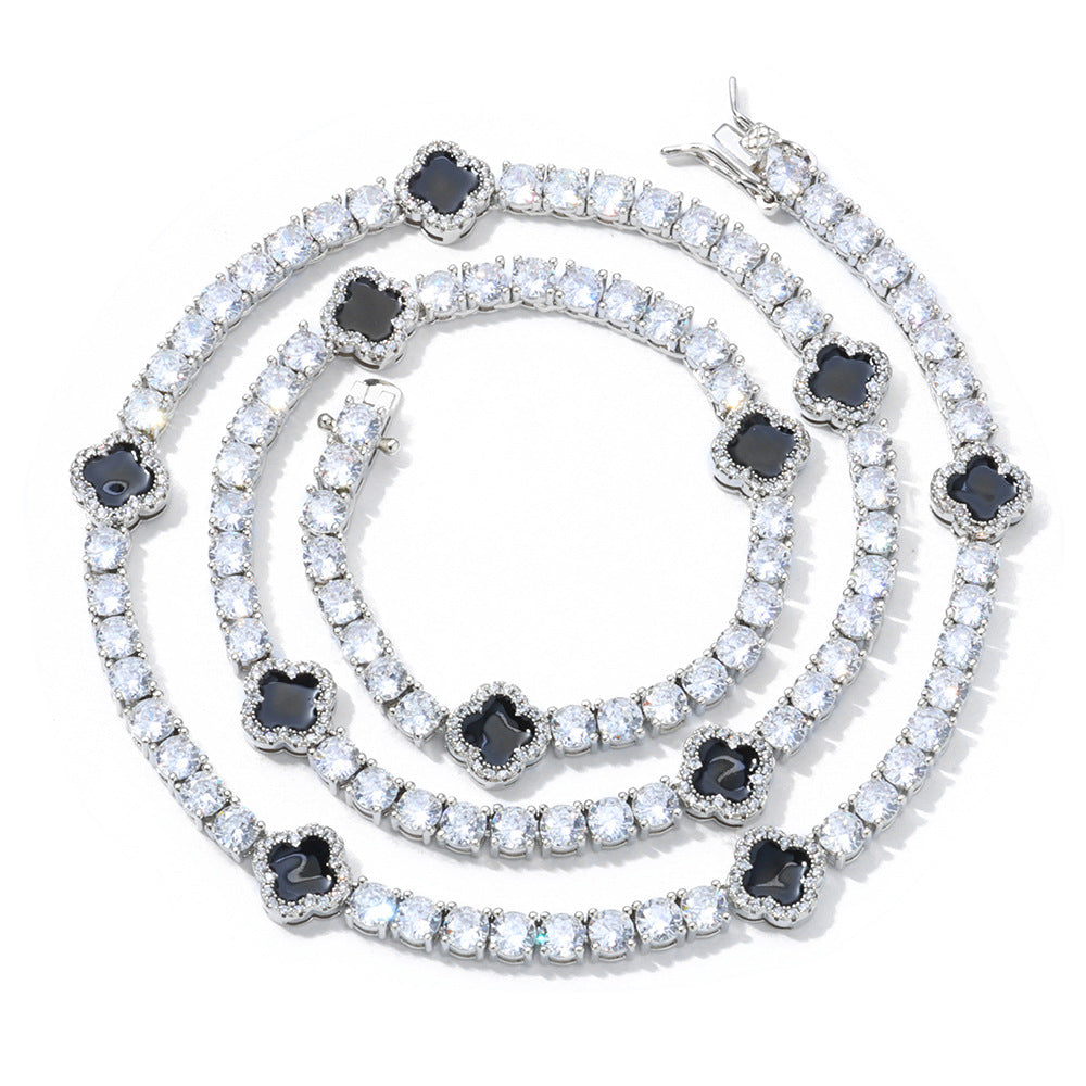 An enamel clover motifs tennis necklace. Black enamel clover motifs with white zirconias. Brass with silver plating.