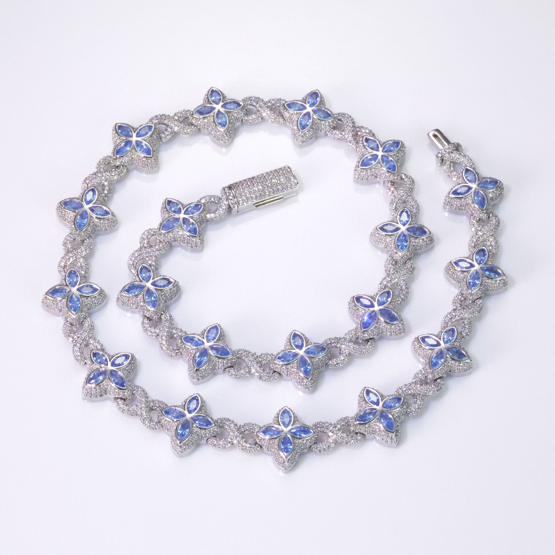 An iced out luxury big clover necklace, infinity symbol, design in clovers with blue maquise stone. Iced out box clasp. Brass with silver plating.