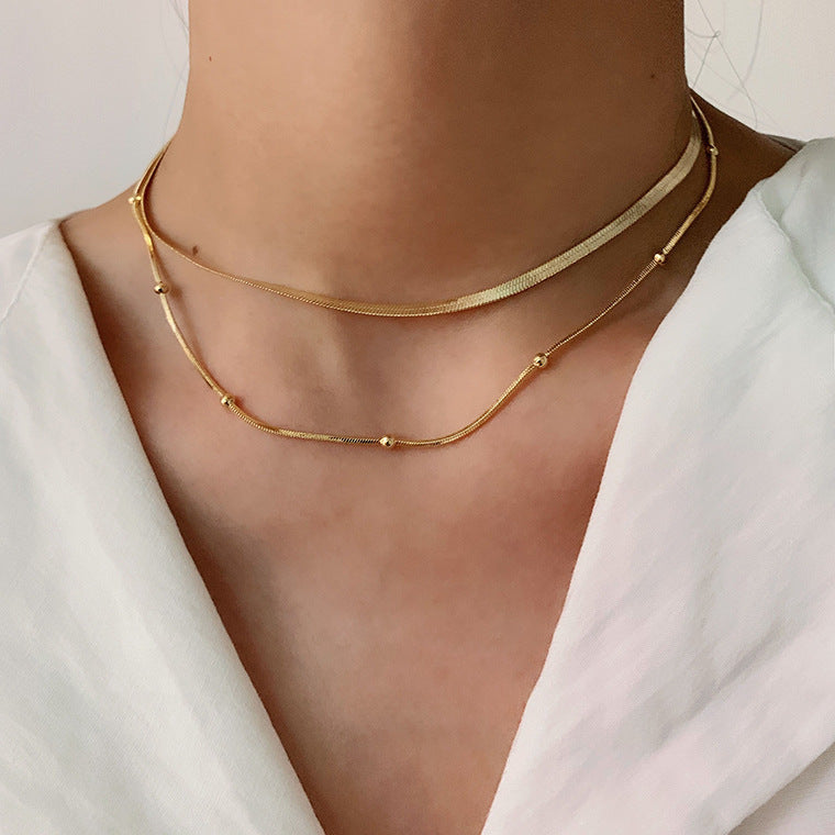 The model showcases the layered snake chain choker with gold plating.