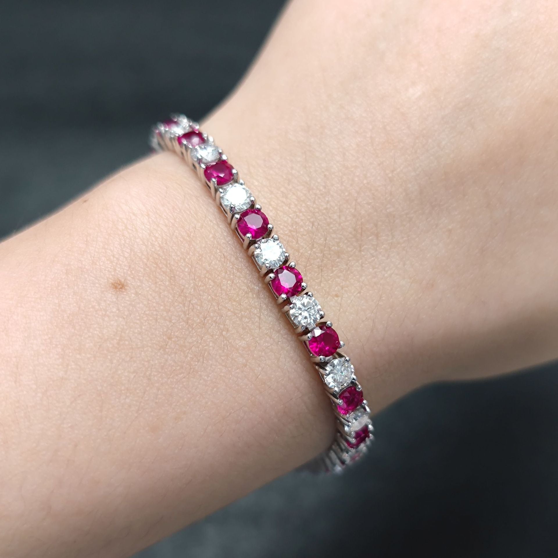 The model showcases the ruby mossanite tennis bracelet with rhodium plating.