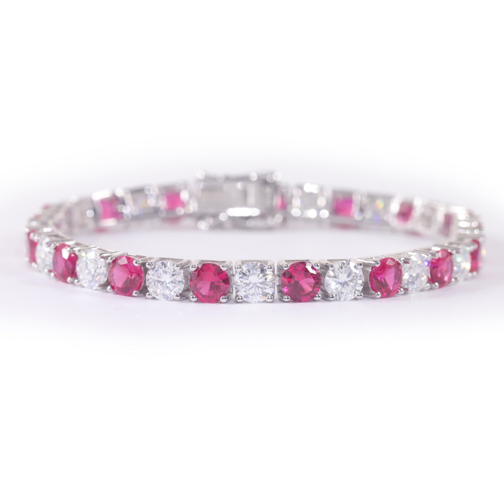 A sterling silver tennis bracelet alternating between synthetic rubies and moissanite. Plating with rhodium.