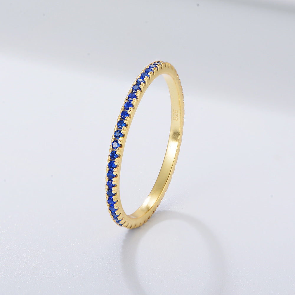 A sterling silver eternity ring band, inlaid with blue zirconias. Plating with gold.