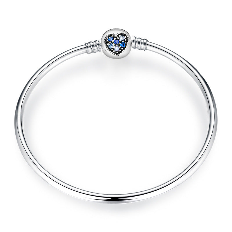 A sterling silver bangle bracelet, the box clasp design in heart with dark to blue zirconias.