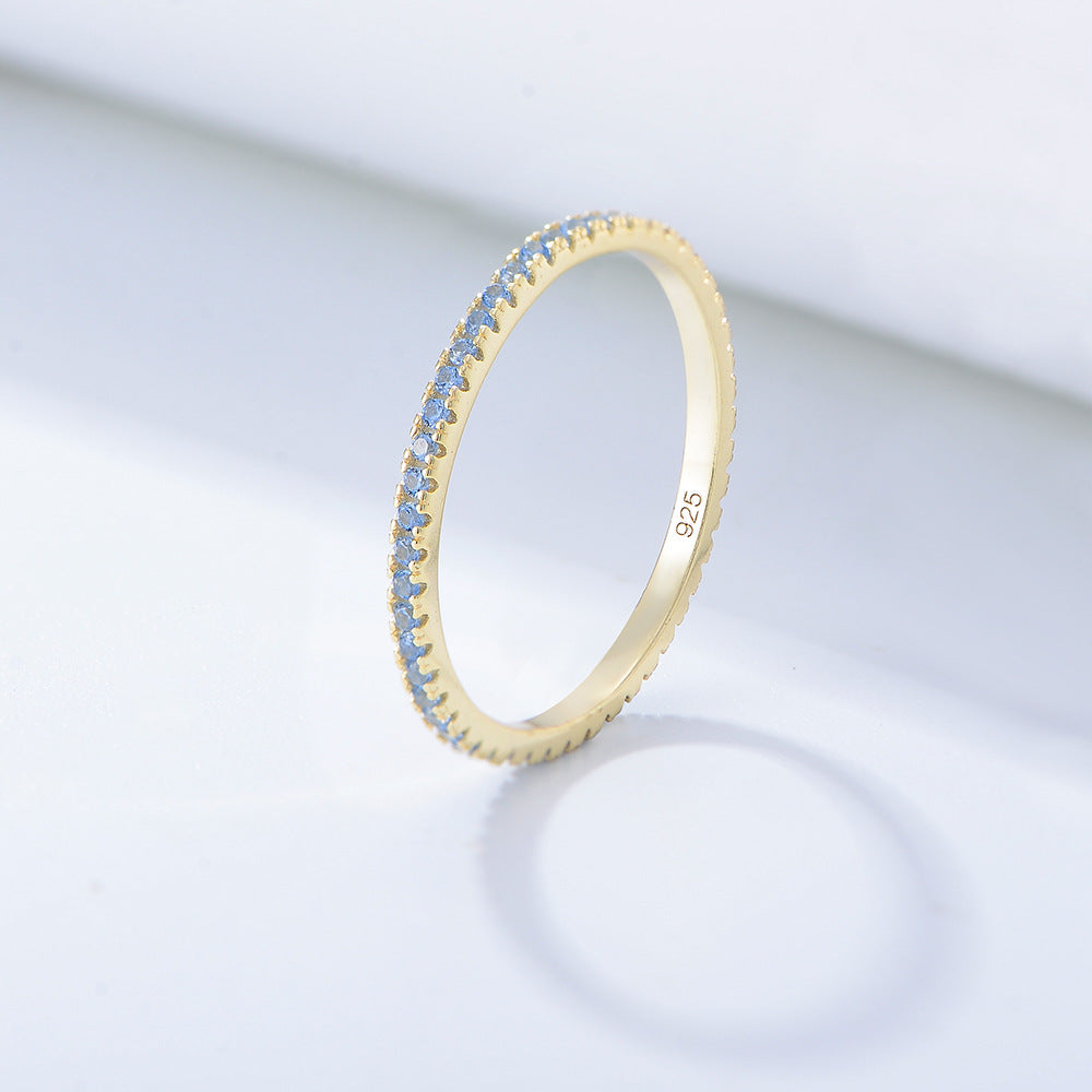 A sterling silver eternity ring band, inlaid with light blue zirconias. Plating with gold.