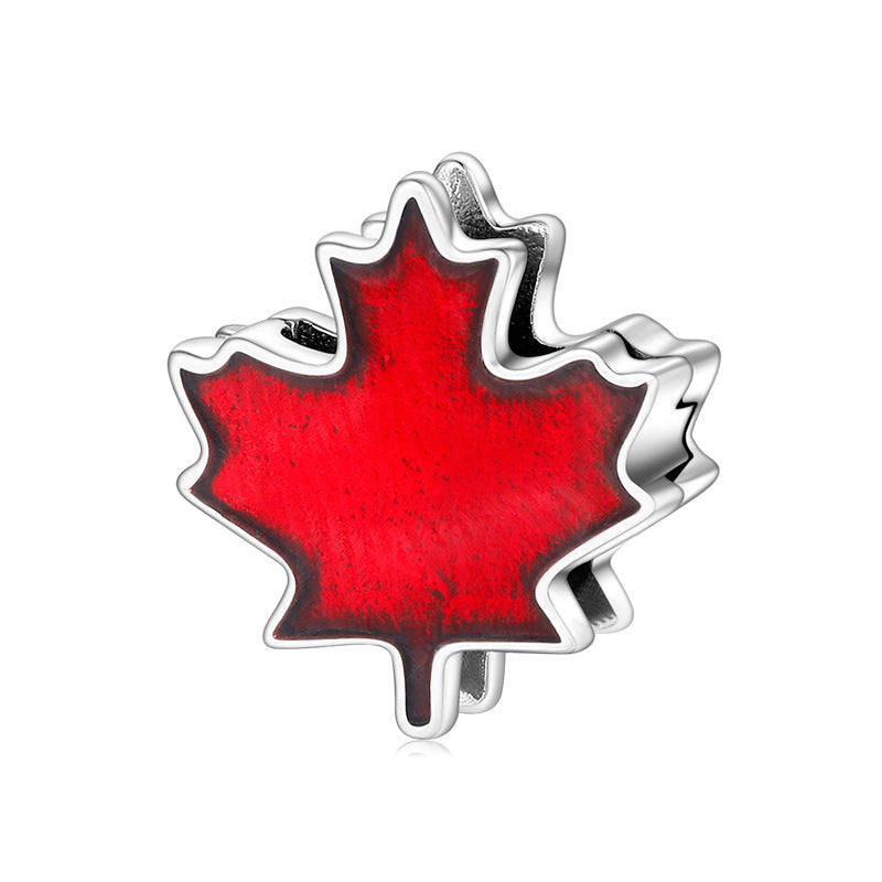 A sterling silver red enamel maple leaf charm