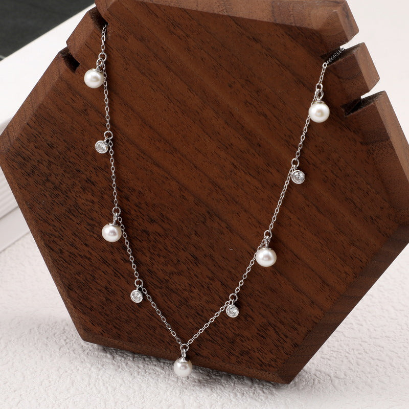 A silver pearl choker. Cable chain with many hanging white zirconia and pearl.