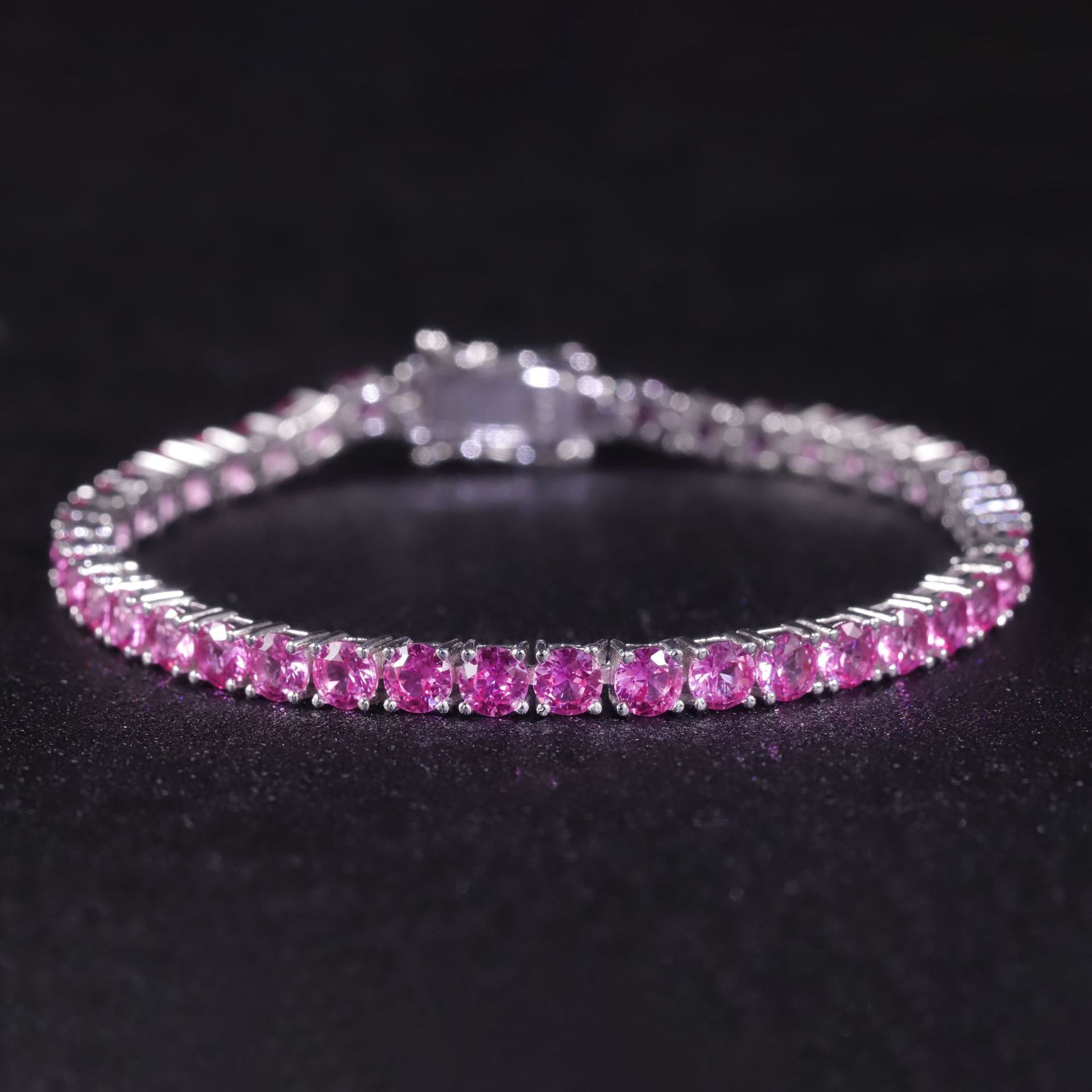 A sterling silver tennis bracelet with pink synthetic sapphire. Plating with rhodium.