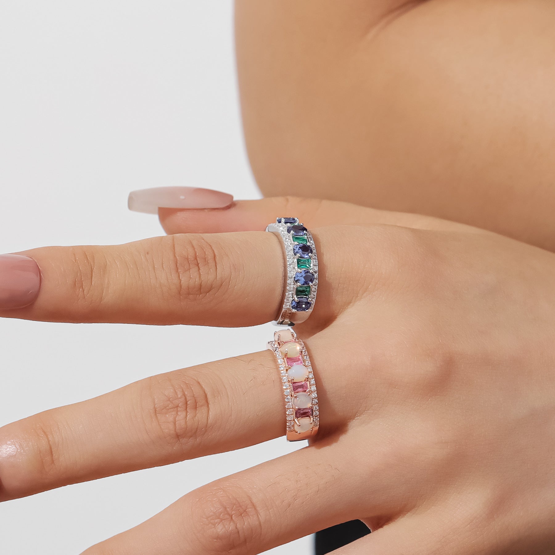 The model showcases the synthetic sapphire ring and the natural opal ring.