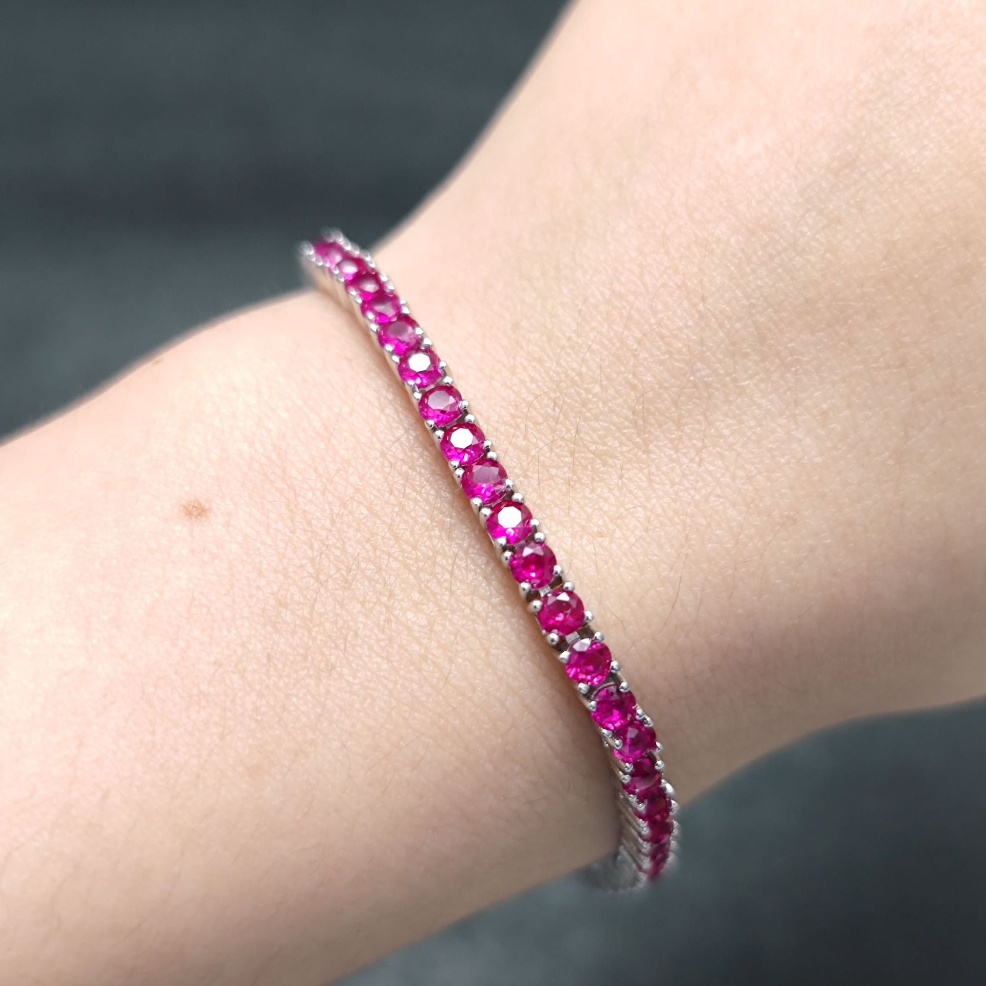 The model showcases the synthetic ruby tennis bracelet. Plating with rhodium.