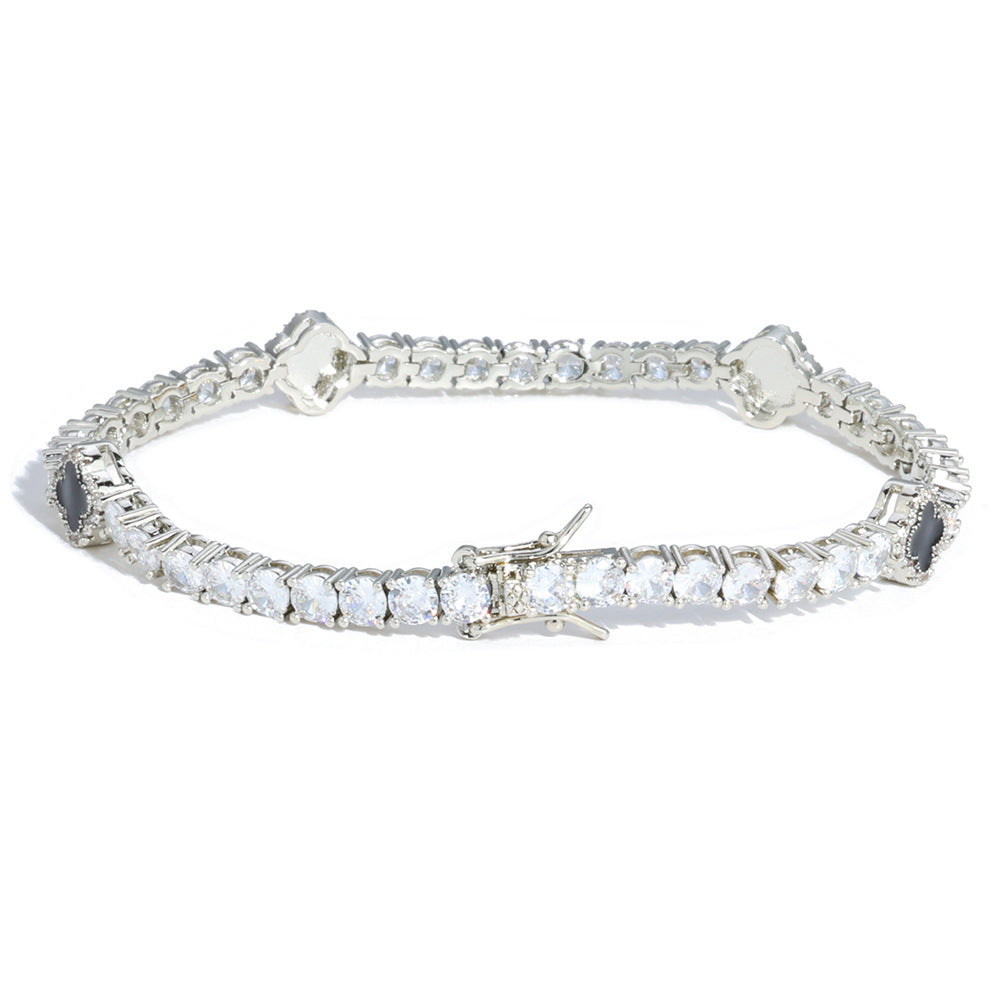 An enamel clover motifs tennis bracelet.  Black enamel clover motifs with white zirconias. Brass with silver plating.
