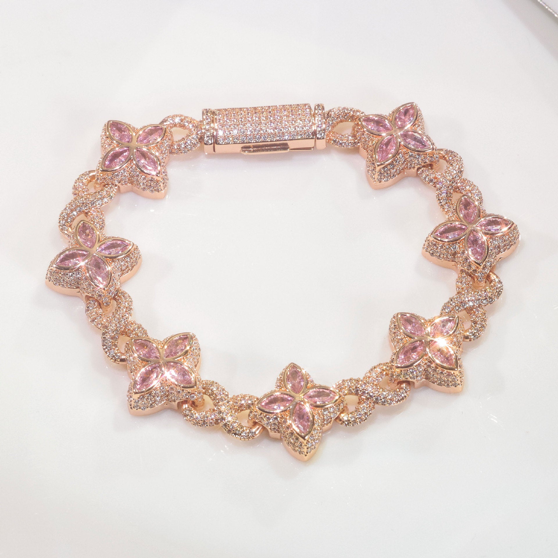 An iced out luxury big clover bracelet, infinity symbol, design in clovers with pink maquise stone. Iced out box clasp. Brass with rose gold plating.
